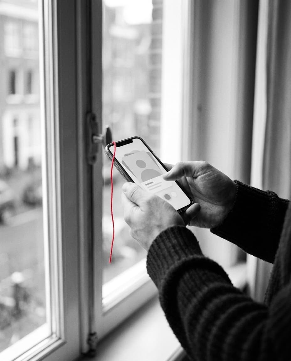 Handen met een telefoon bij het raam — een profiel aanmaken